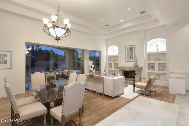 dining room featuring a chandelier, built in shelves, visible vents, and wood finished floors