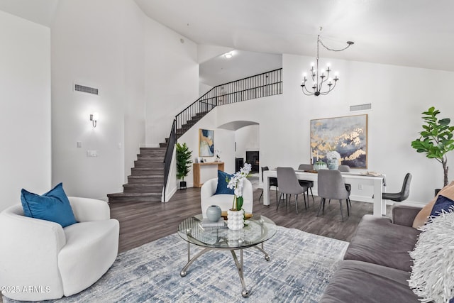 living room with wood-type flooring, high vaulted ceiling, and a chandelier