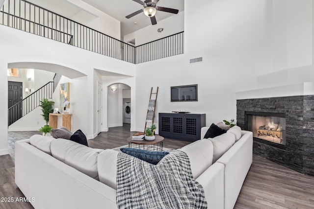 living room with washer / dryer, hardwood / wood-style floors, and a stone fireplace