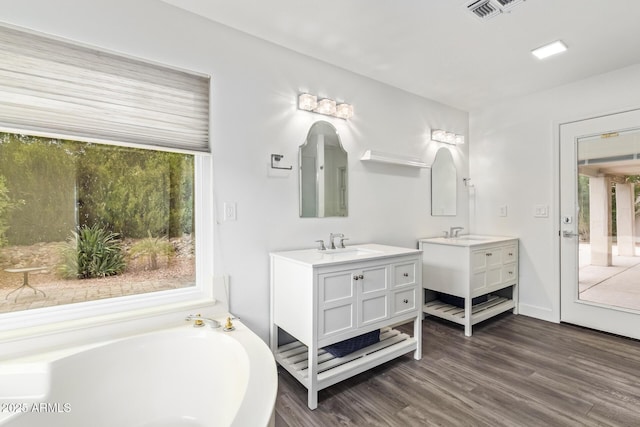 bathroom with a tub to relax in, vanity, and hardwood / wood-style floors