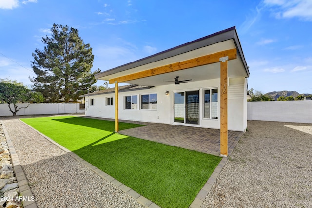 rear view of property with a ceiling fan, a fenced backyard, a yard, and a patio