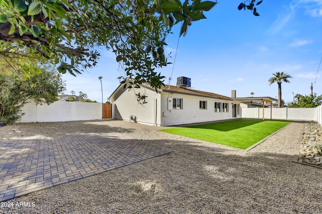 back of property featuring a patio, stucco siding, a lawn, central AC, and a fenced backyard