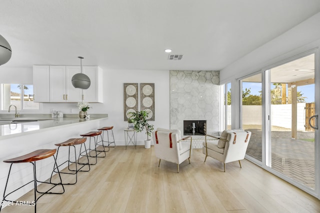 living area with visible vents, baseboards, a stone fireplace, light wood-style floors, and recessed lighting