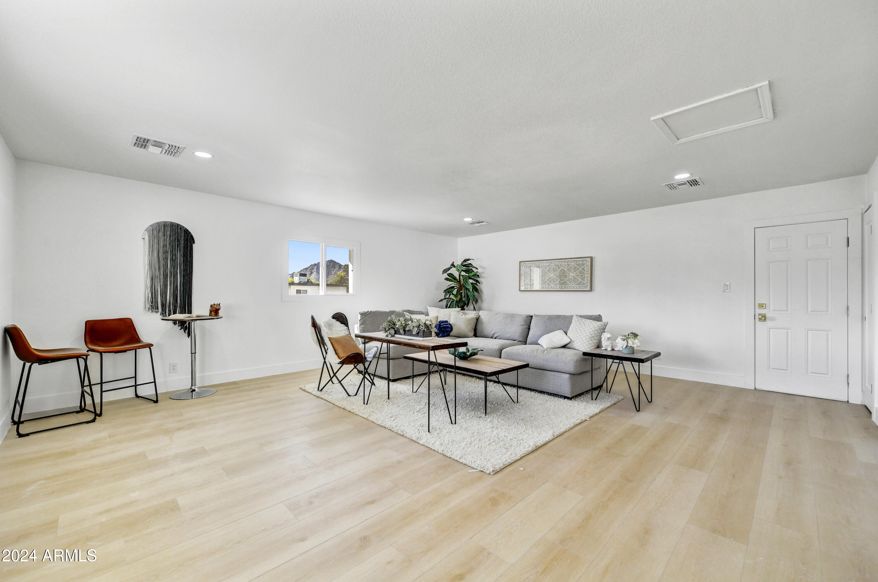 living area featuring baseboards, wood finished floors, visible vents, and attic access