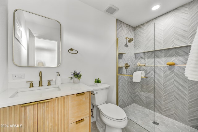 bathroom with toilet, visible vents, tiled shower, and vanity