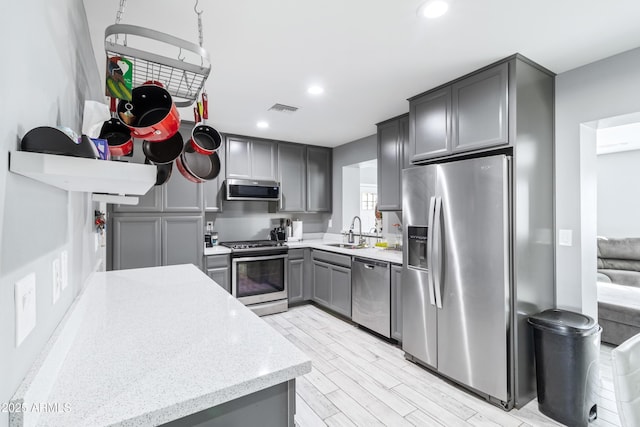 kitchen featuring light wood-type flooring, stainless steel appliances, gray cabinets, and sink