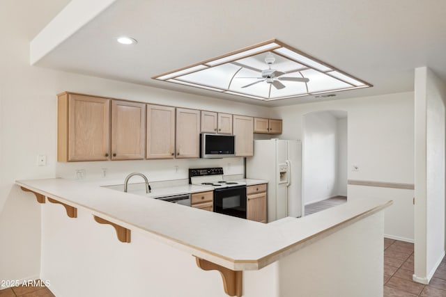 kitchen featuring kitchen peninsula, a kitchen bar, white appliances, and ceiling fan