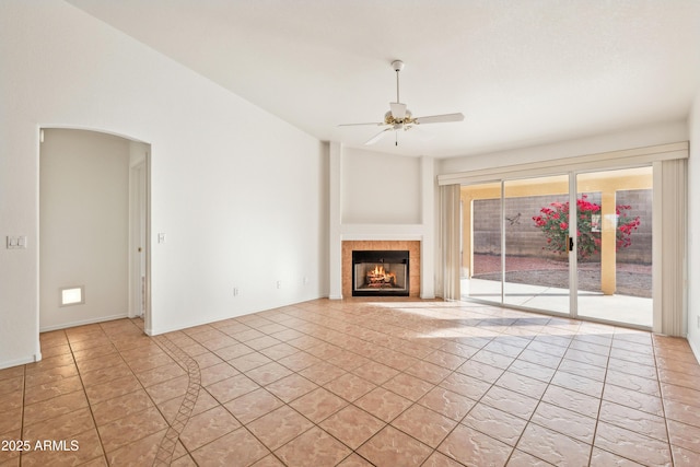 unfurnished living room featuring a tile fireplace, ceiling fan, and light tile patterned floors