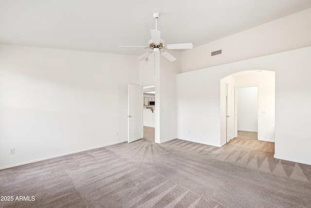 carpeted spare room with ceiling fan and high vaulted ceiling