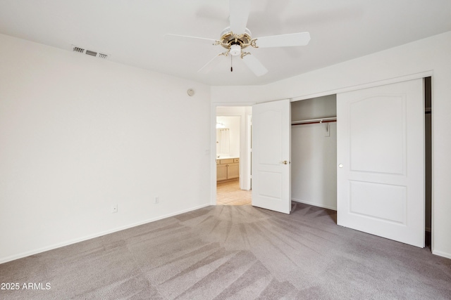 unfurnished bedroom with ceiling fan, light carpet, and a closet