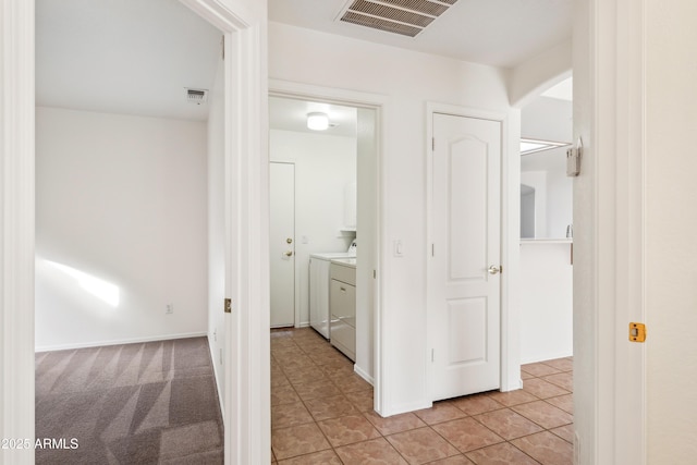 hallway with light tile patterned floors and separate washer and dryer