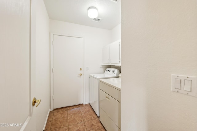 clothes washing area featuring washer and clothes dryer, cabinets, and light tile patterned floors