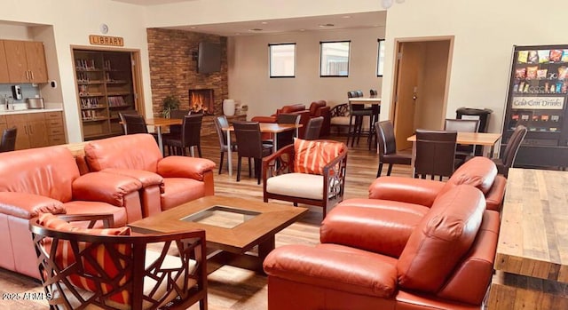 living room with a stone fireplace and light wood-type flooring