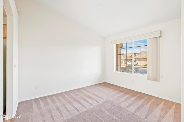 carpeted empty room featuring vaulted ceiling