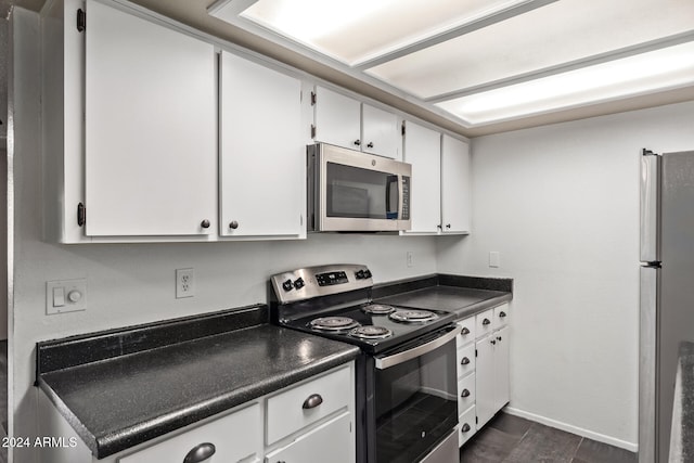 kitchen with appliances with stainless steel finishes, dark hardwood / wood-style floors, and white cabinetry