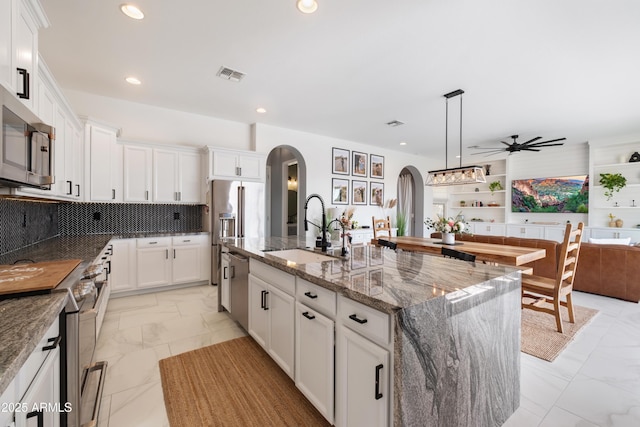 kitchen featuring sink, hanging light fixtures, a center island with sink, appliances with stainless steel finishes, and white cabinets