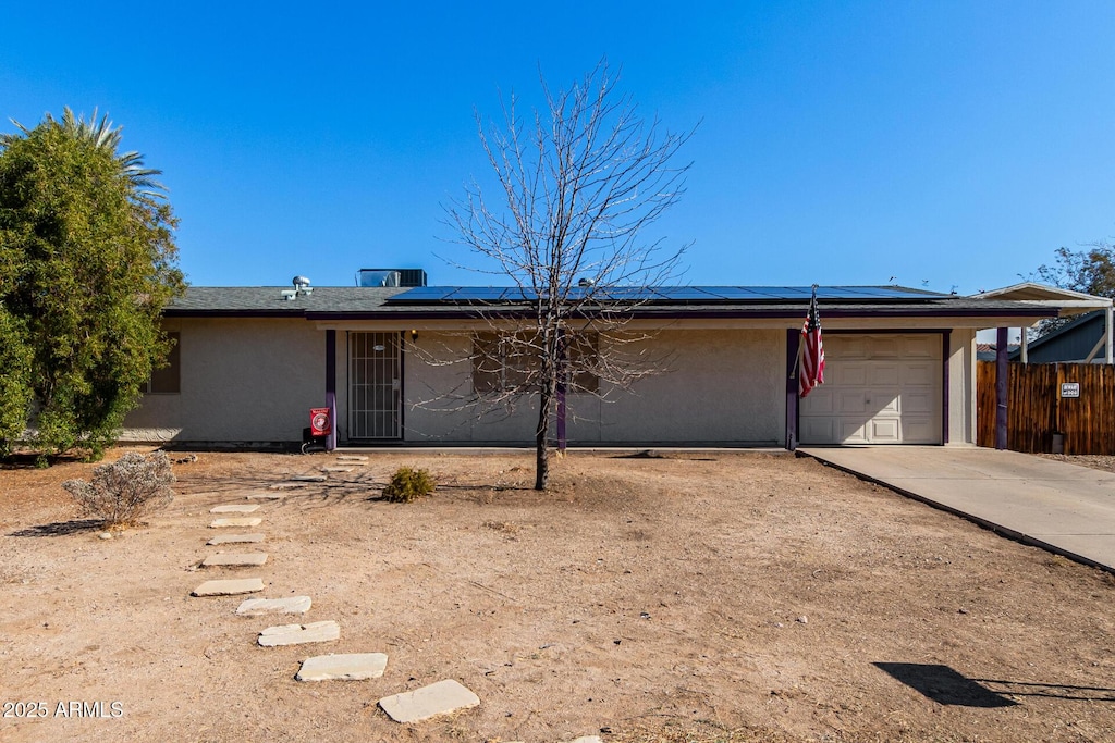 ranch-style house featuring a garage and solar panels