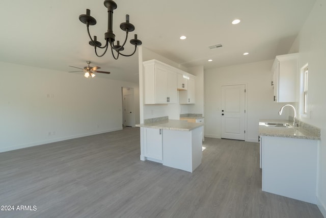 kitchen featuring light hardwood / wood-style floors, ceiling fan with notable chandelier, white cabinetry, light stone countertops, and sink