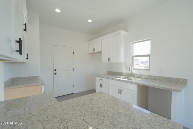 kitchen with white cabinetry, sink, and light stone counters