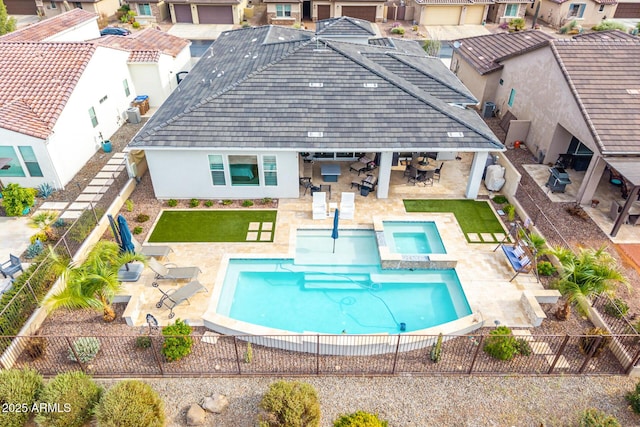 rear view of property with a pool with connected hot tub, a fenced backyard, a patio, and stucco siding