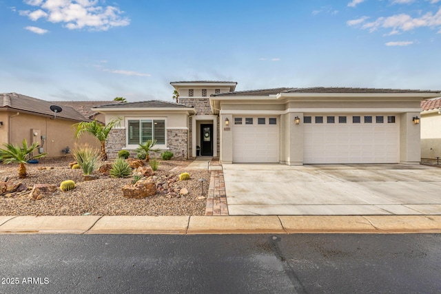 prairie-style home featuring driveway, stone siding, an attached garage, and stucco siding