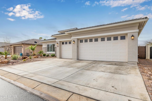 prairie-style home featuring a garage, driveway, fence, and stucco siding