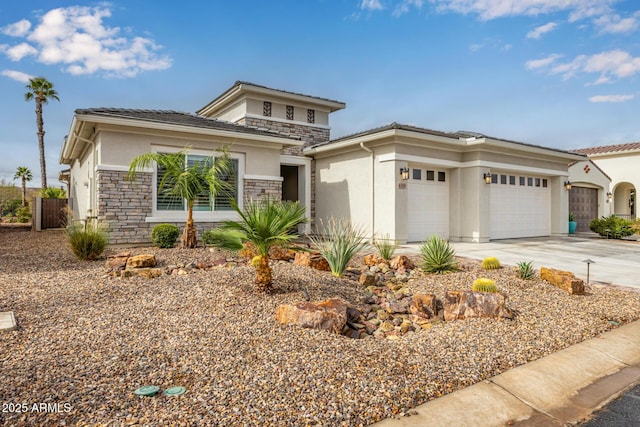 prairie-style house featuring a garage, stone siding, driveway, and stucco siding