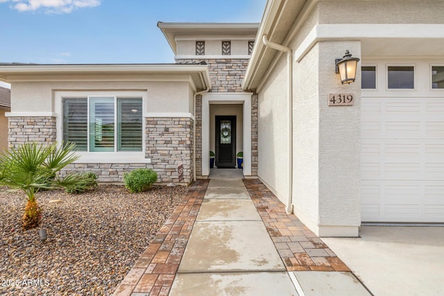 view of exterior entry featuring a garage, stone siding, and stucco siding