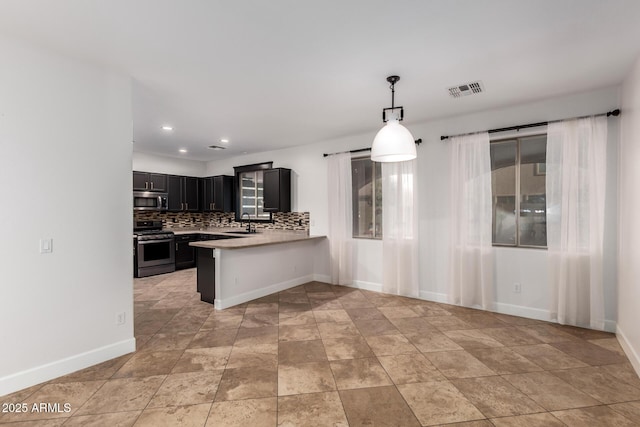 46065 W Meadows Ln, Maricopa, AZ 85139 - kitchen with stainless steel appliances, dark cabinetry, light countertops, backsplash, and a peninsula