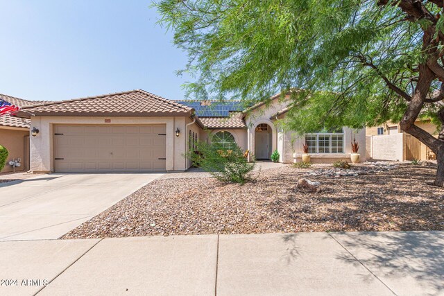 view of front of property with a garage and solar panels