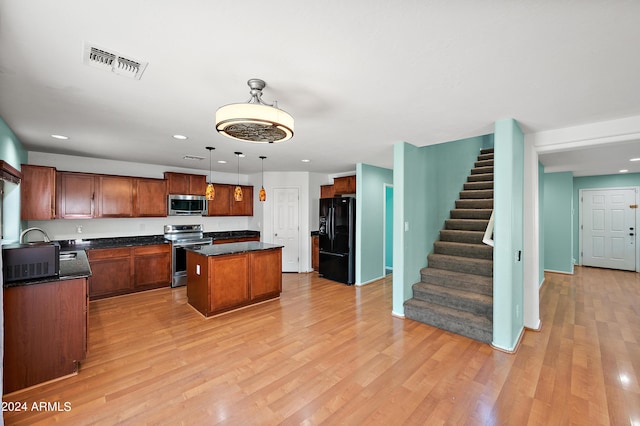 kitchen with visible vents, dark countertops, appliances with stainless steel finishes, a center island, and hanging light fixtures