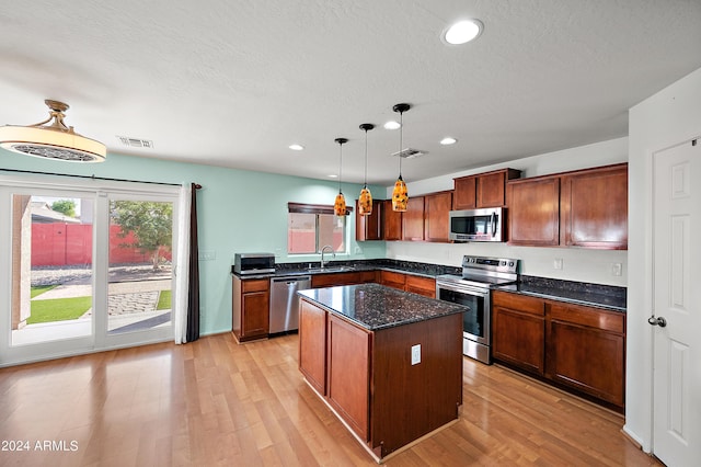 kitchen featuring visible vents, appliances with stainless steel finishes, decorative light fixtures, and a center island