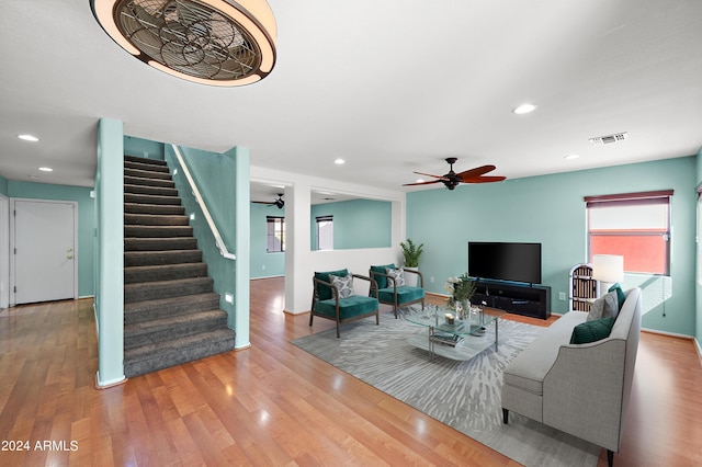 living area with stairway, visible vents, and wood finished floors