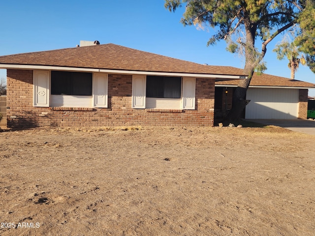 ranch-style house with roof with shingles and brick siding