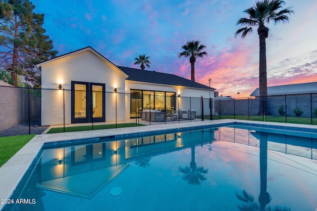 pool at dusk featuring a patio and an outdoor hangout area