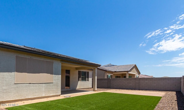 back of house with a fenced backyard, a lawn, a patio, and stucco siding