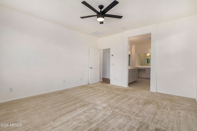 unfurnished bedroom featuring ceiling fan, ensuite bathroom, light carpet, visible vents, and baseboards