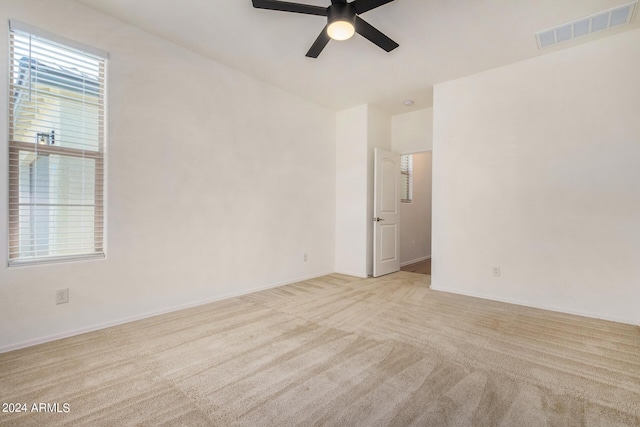 unfurnished room featuring ceiling fan, carpet, visible vents, and a healthy amount of sunlight