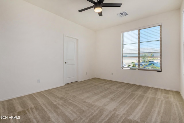 spare room with light carpet, ceiling fan, visible vents, and baseboards