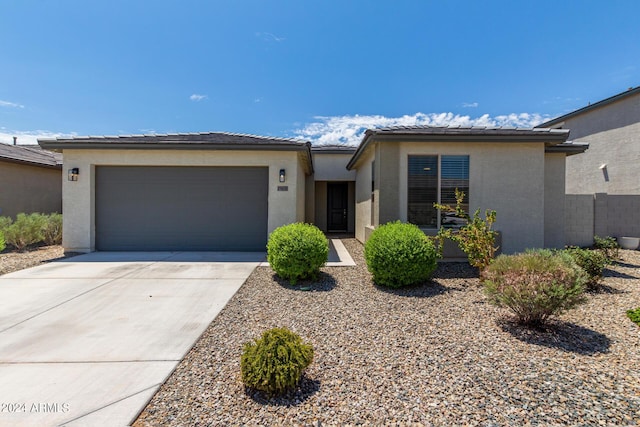 view of front of property featuring concrete driveway, an attached garage, a tile roof, and stucco siding