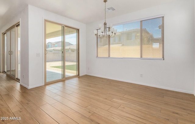 unfurnished dining area with a notable chandelier, baseboards, visible vents, and light wood-style floors