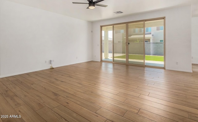 unfurnished room with a ceiling fan, a wealth of natural light, visible vents, and wood finished floors