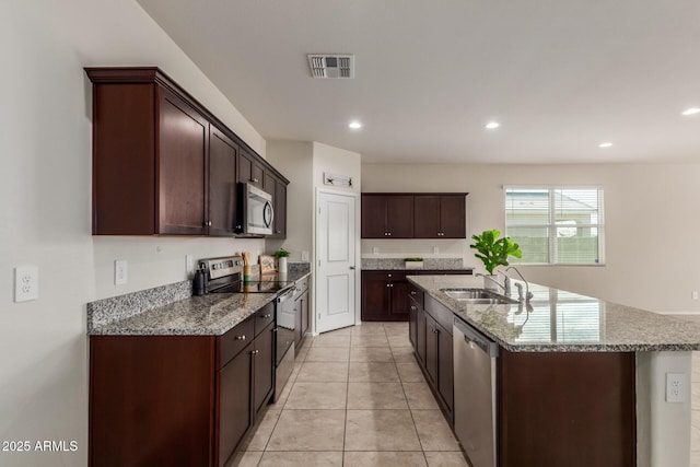 kitchen featuring visible vents, stone countertops, a sink, a kitchen island with sink, and appliances with stainless steel finishes