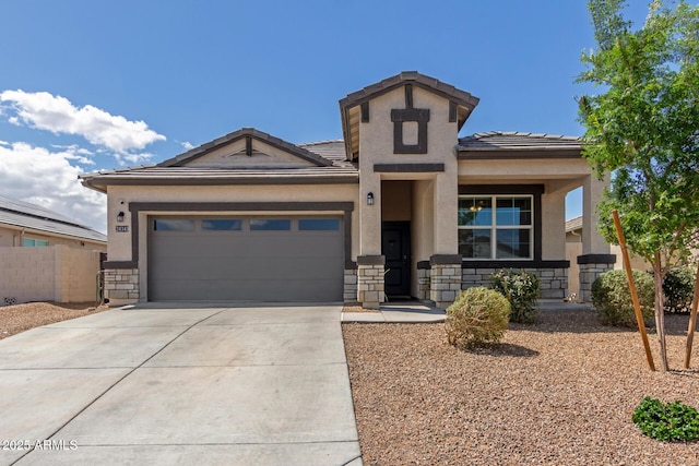 view of front of property with concrete driveway, stone siding, a tiled roof, an attached garage, and stucco siding