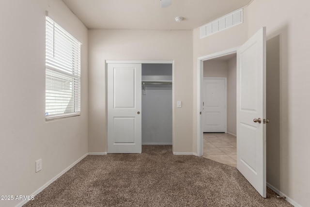 unfurnished bedroom with baseboards, carpet floors, visible vents, and a closet