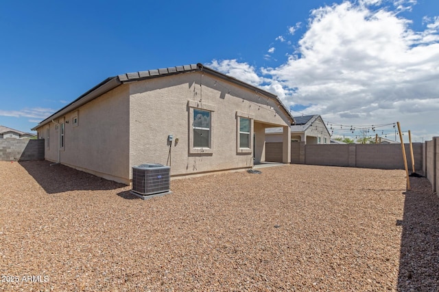 rear view of house featuring cooling unit, a fenced backyard, and stucco siding