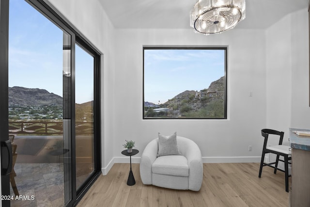 living area featuring a mountain view, an inviting chandelier, and light hardwood / wood-style flooring