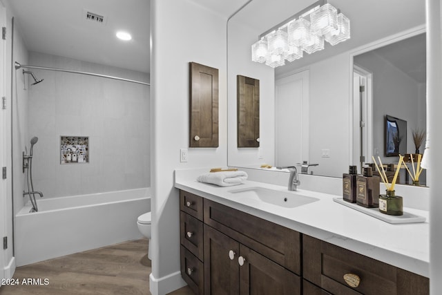 full bathroom with vanity, hardwood / wood-style floors, tiled shower / bath combo, and toilet