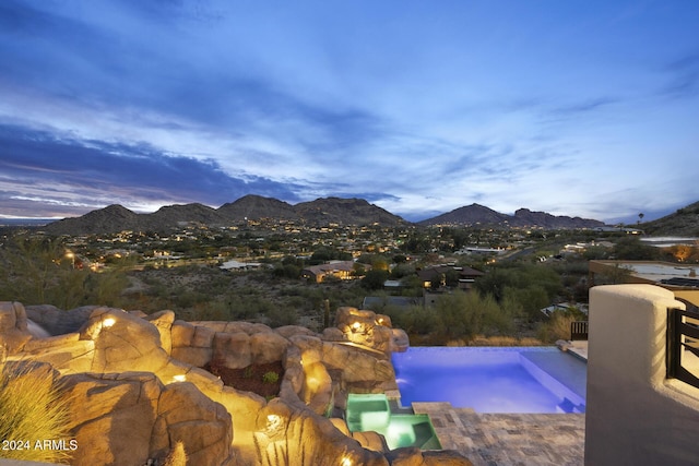 pool at dusk with a mountain view and an in ground hot tub