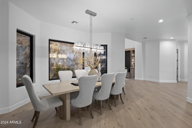 dining area with light hardwood / wood-style floors and an inviting chandelier